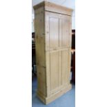 A Victorian pine tall cupboard with eight adjustable shelves enclosed by two panel doors, & on