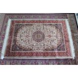 A Keshan rug of ivory & crimson ground & with all-over repeating multi-coloured geometric design,