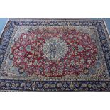 A Persian carpet of crimson, ivory, & deep blue ground, with central medallion surrounded by