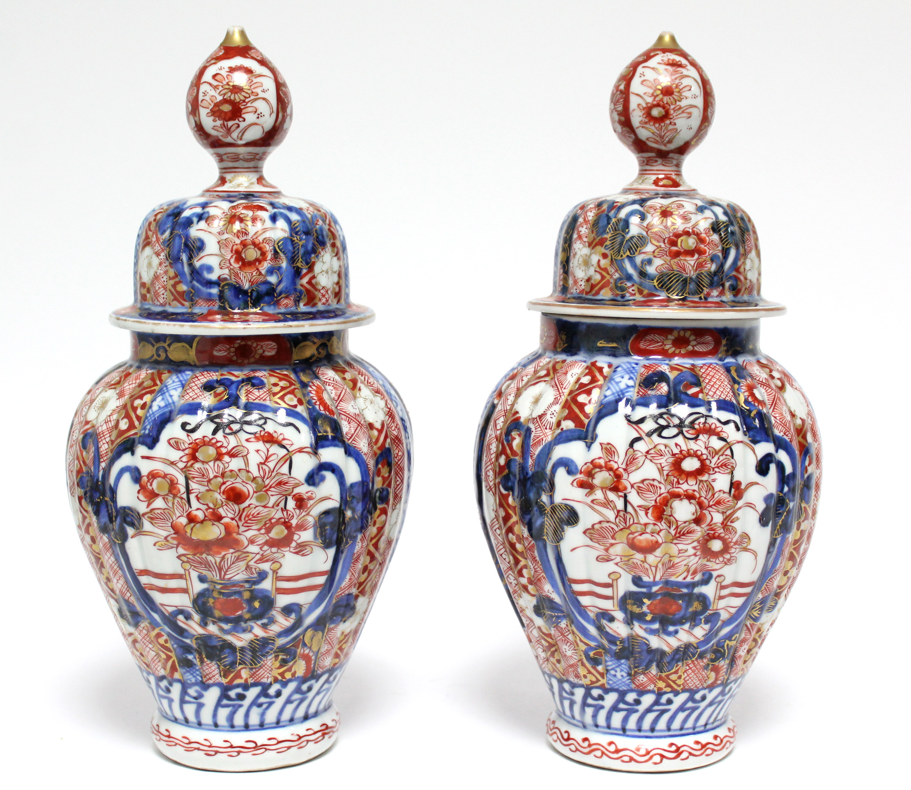 A pair of 19th century Japanese Imari fluted baluster vases with domed covers; 12” high.
