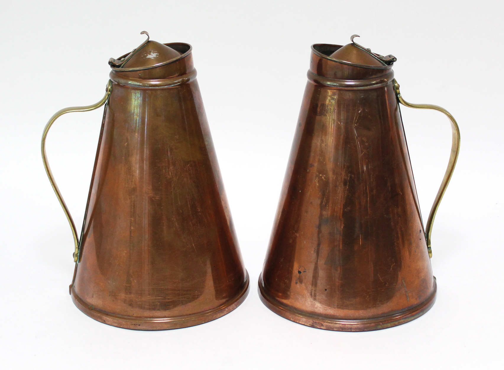A pair of W. A. S. Benson Arts & Crafts copper “Jacketed Jugs” of tapered cylindrical form, with