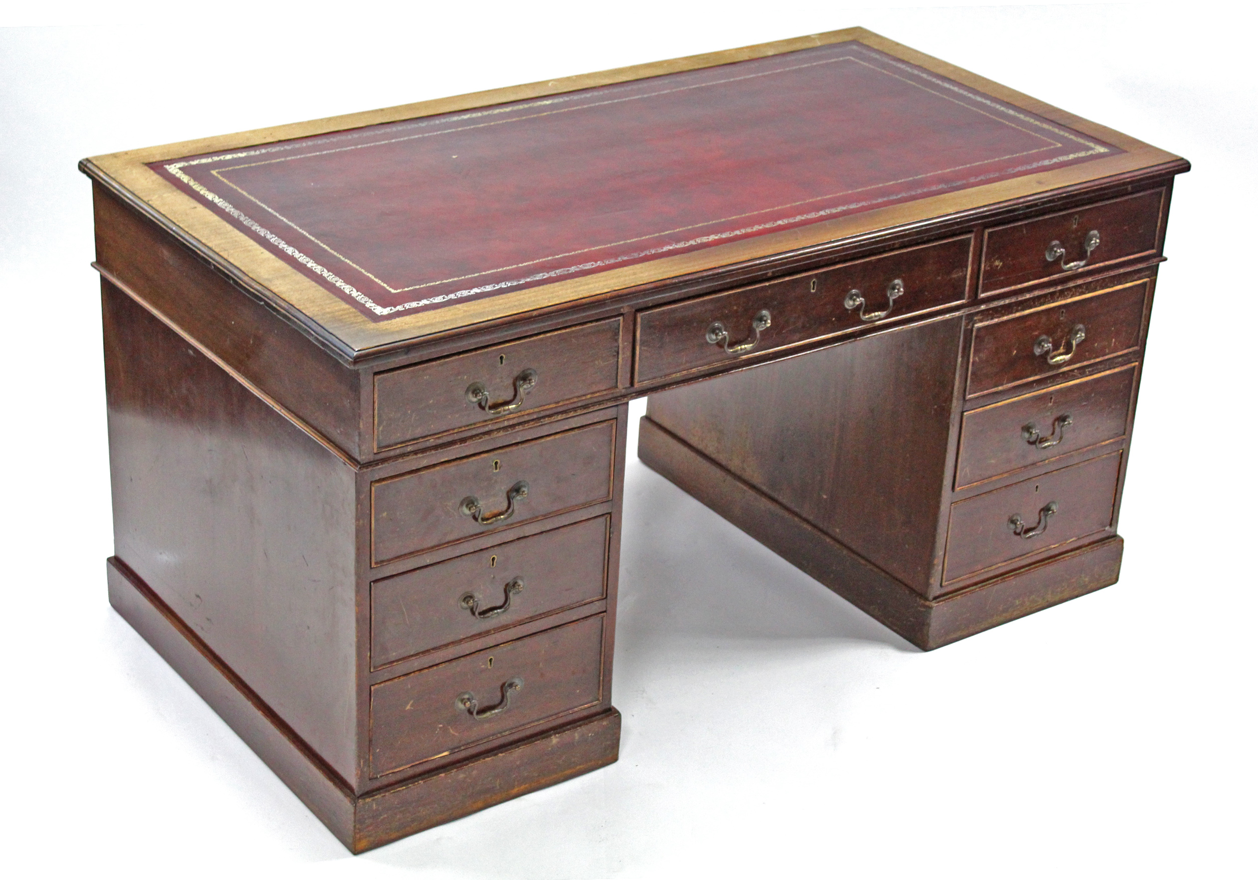 A George V mahogany pedestal desk with crimson tooled leather top, fitted nine drawers with brass