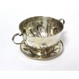 An Edwardian two-handled porringer & paten, both with embossed scroll decoration; London 1905 by