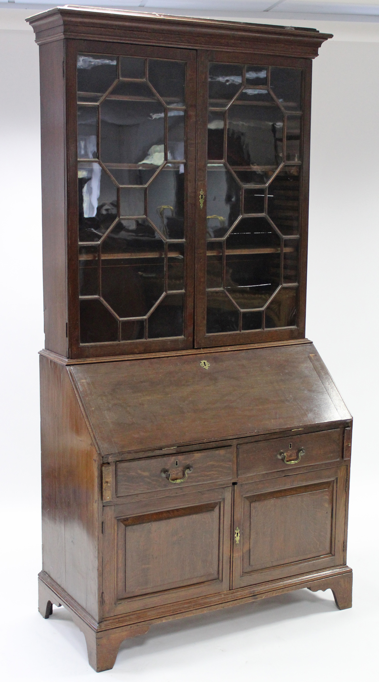 An 18th century oak bureau-bookcase, the upper part fitted three adjustable shelves enclosed by pair