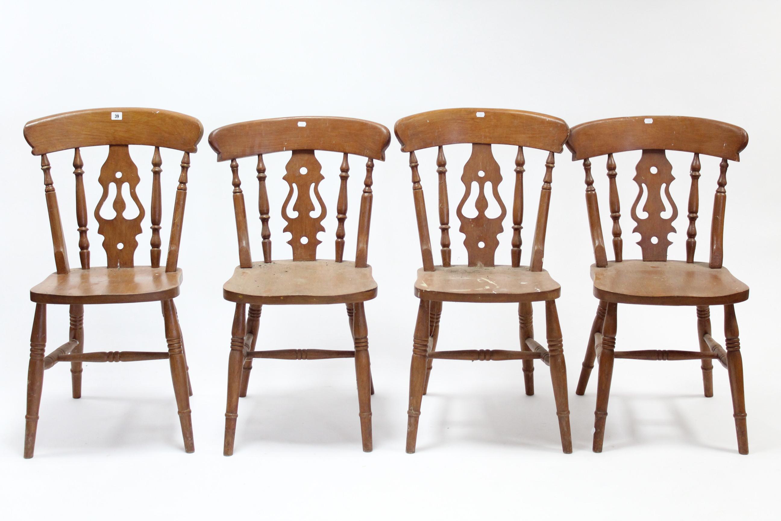 A set of four splat-back kitchen chairs with hard seats, & on turned legs with turned stretchers.