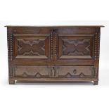 A 19th century oak coffer with hinged lift-lid, & with carved panel front above a long drawer (