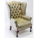 A Victorian-style pale green leather & brass studed wing-back armchair, with buttoned-back, loose