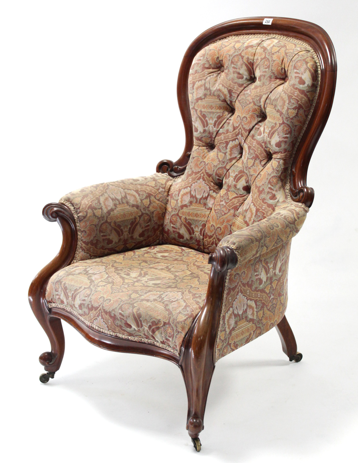 A Victorian carved mahogany-frame armchair with buttoned spoon-shaped back & sprung seat upholstered