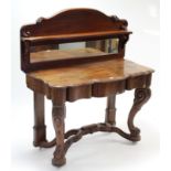 A mahogany serpentine-front dressing table inset rectangular mirror to the stage back, fitted centre