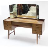 A mid-20th century teak kneehole dressing table with triple-panel mirror back, fitted with an
