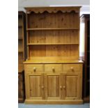 A pine dresser, the upper part fitted two open shelves, & with panelled back, the base fitted