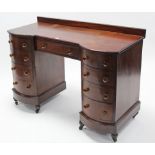A mahogany inverted break-front kneehole dressing table fitted with an arrangement of nine