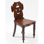 A Victorian mahogany hall chair with carved & pierced shaped back, serpentine-front hard seat, &