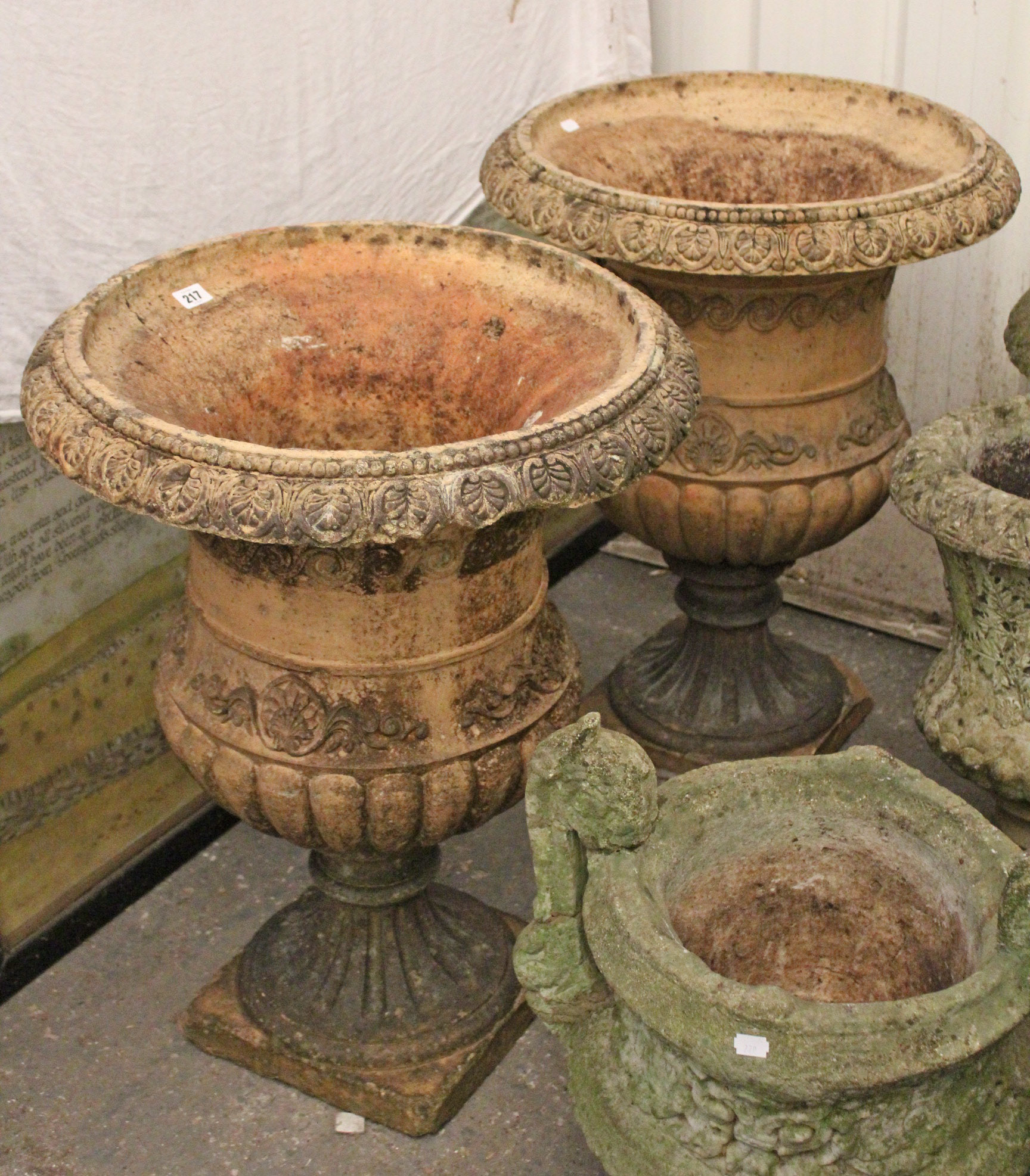 A pair of terracotta garden flower pots of ovoid form, with raised geometrical design, & on square