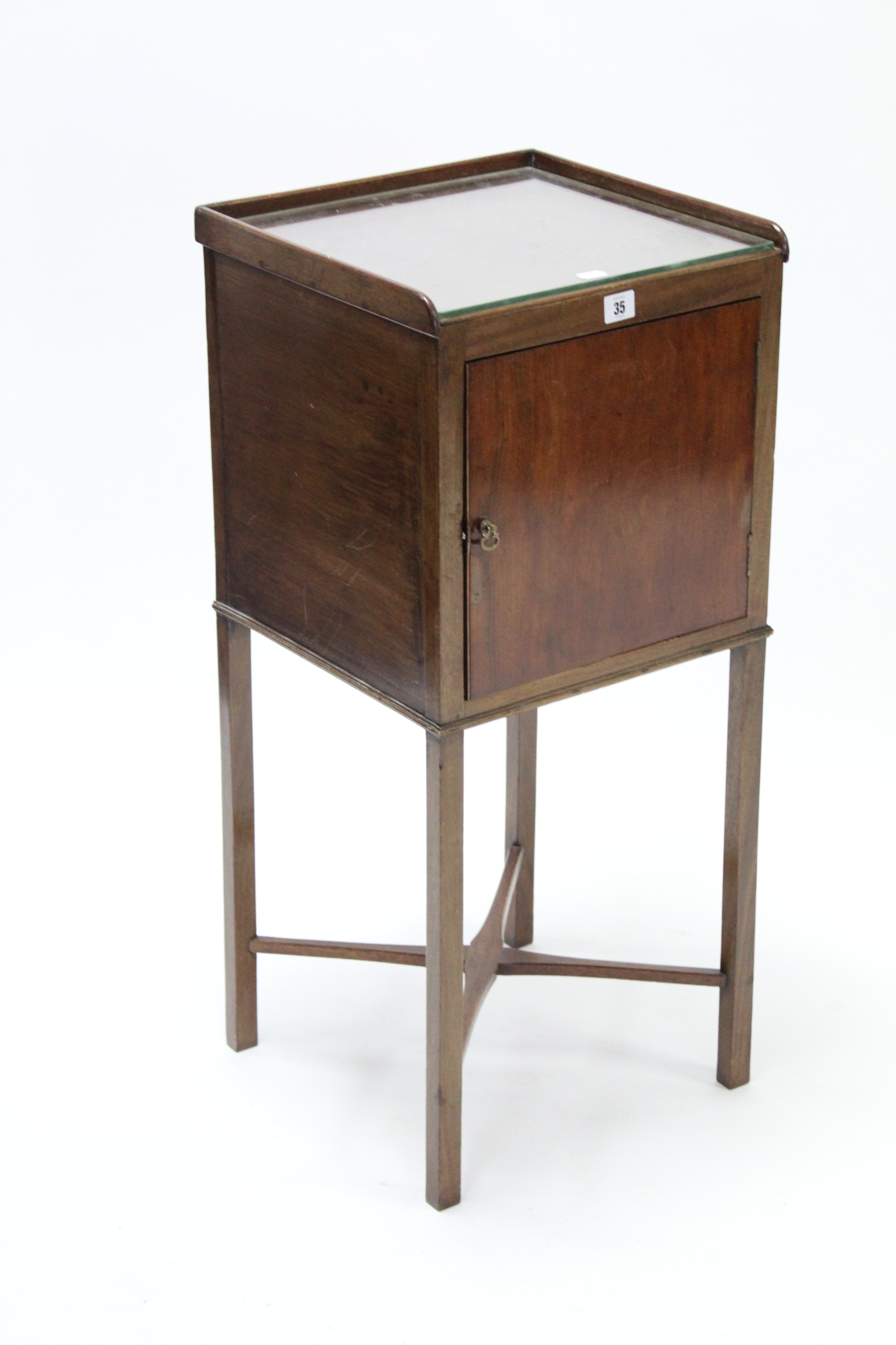 A late 19th/early 20th century mahogany tray-top bedside cabinet enclosed by panel door, & on square
