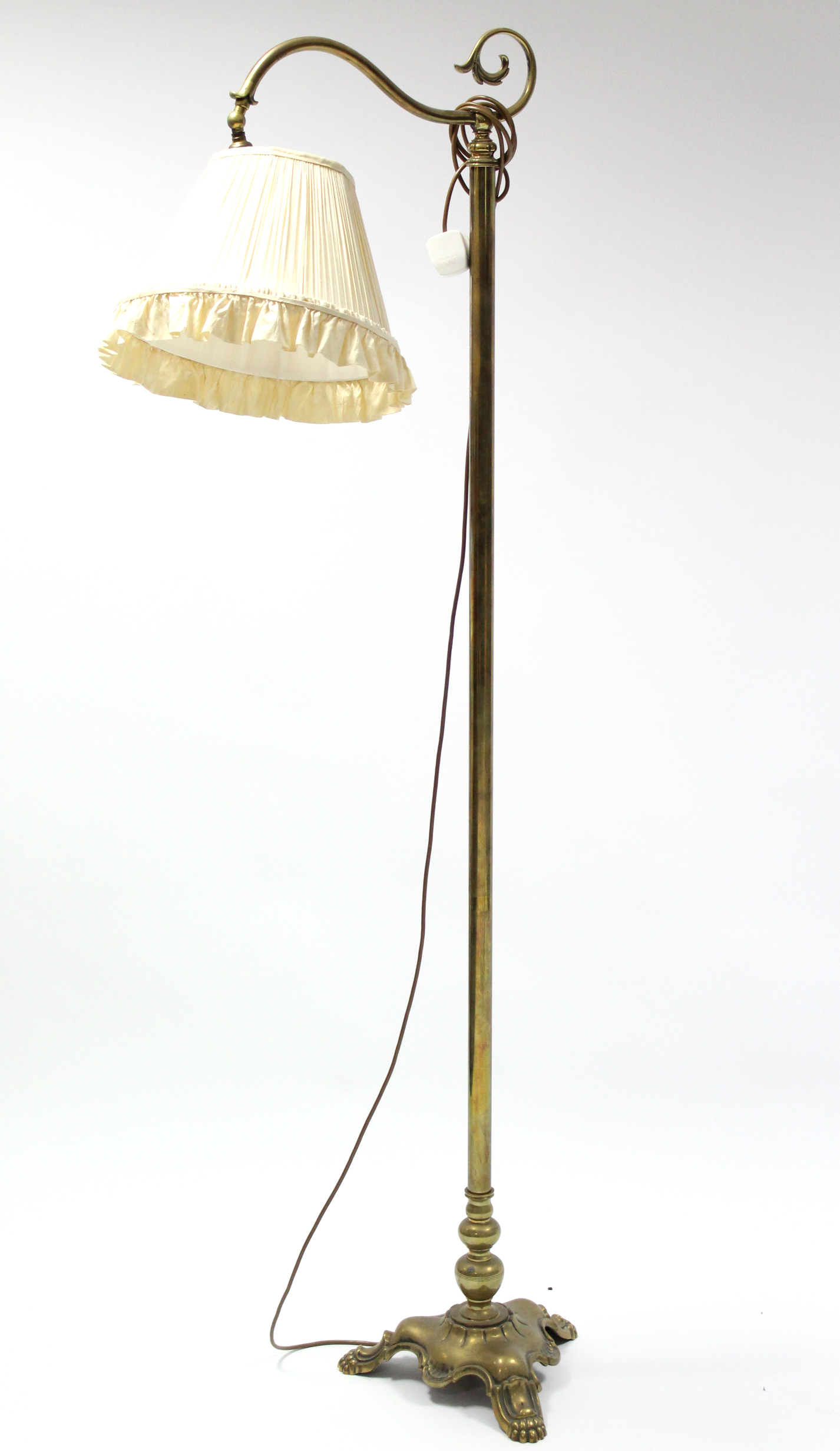 An Edwardian brass standard lamp with scroll arm, on triform base with lion paw feet; 5’6” high; & a