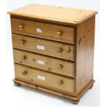 A pine small chest fitted four long drawers with turned knob handles, & on bun feet, 32” wide x