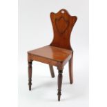 An early 19th century mahogany hall chair with shield-shaped back, hard seat, & on turned tapered