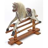 A dapple-grey painted wooden child’s rocking horse on pine trestle base, 34” long x 32” high.