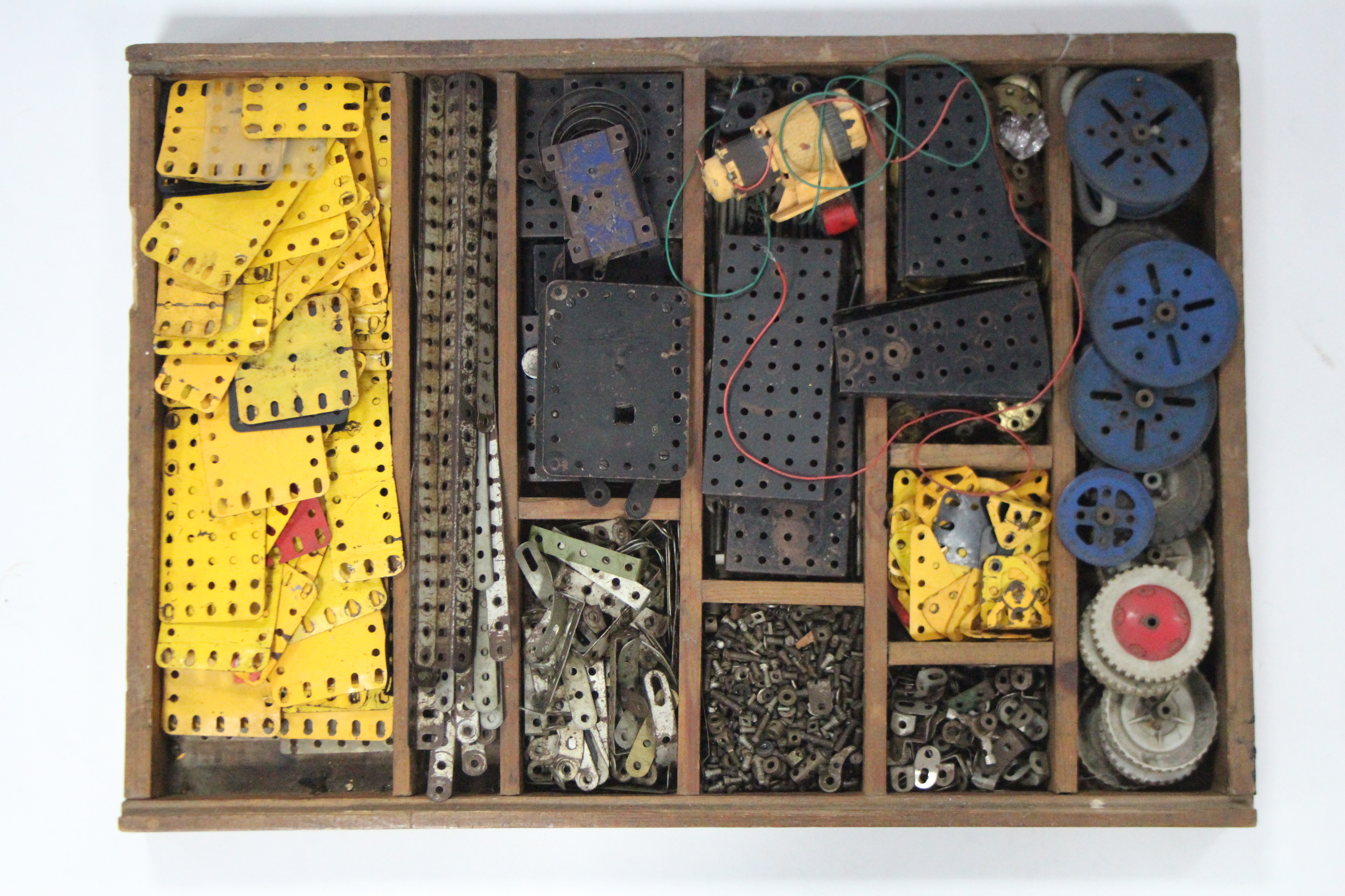 Various items of loose Meccano, contained in a wooden tray.