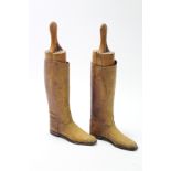 A pair of tan leather riding boots with oak trees.