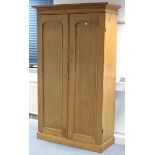 A pine wardrobe with hanging compartment above a long drawer enclosed by pair of panel doors; & on