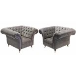 A large pair of buttoned grey velour armchairs, on mahogany short turned legs with brass castors.