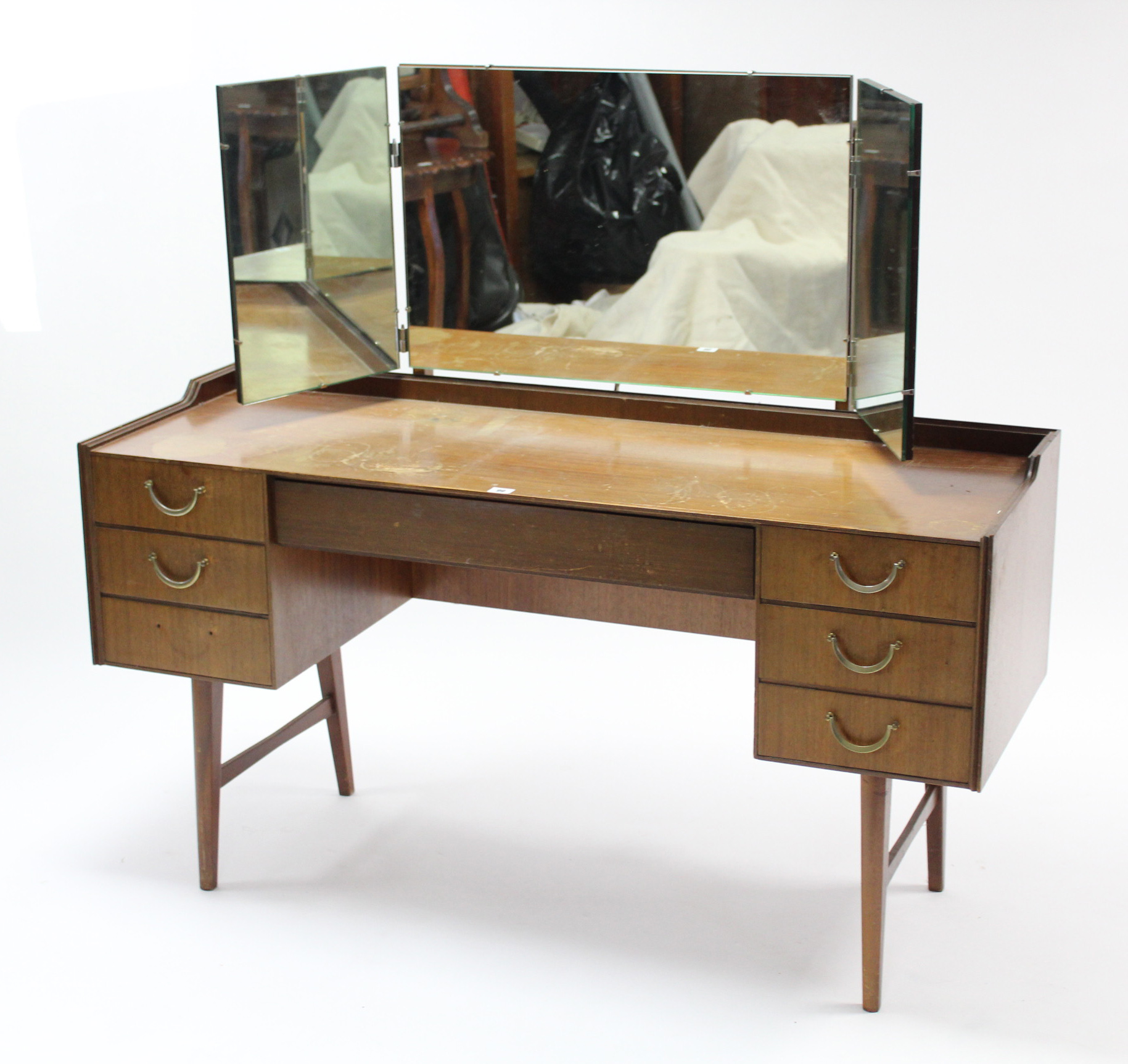 A mid-20th century teak kneehole dressing table with triple-panel mirror back, fitted with an