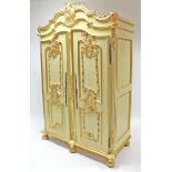 A reproduction continental-style cream & gold painted wooden armoire with carved surmount,