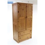A pine wardrobe enclosed by pair of panel doors above two long drawers, 37¼” wide x 73” high.