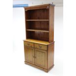 A pine dresser the upper part fitted two open shelves & with panelled back, the base fitted two