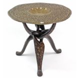 An Eastern brass embossed circular tray-top occasional table on carved wooden folding stand, 30”