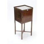 A late 19th/early 20th century mahogany tray-top bedside cabinet enclosed by panel door, & on square