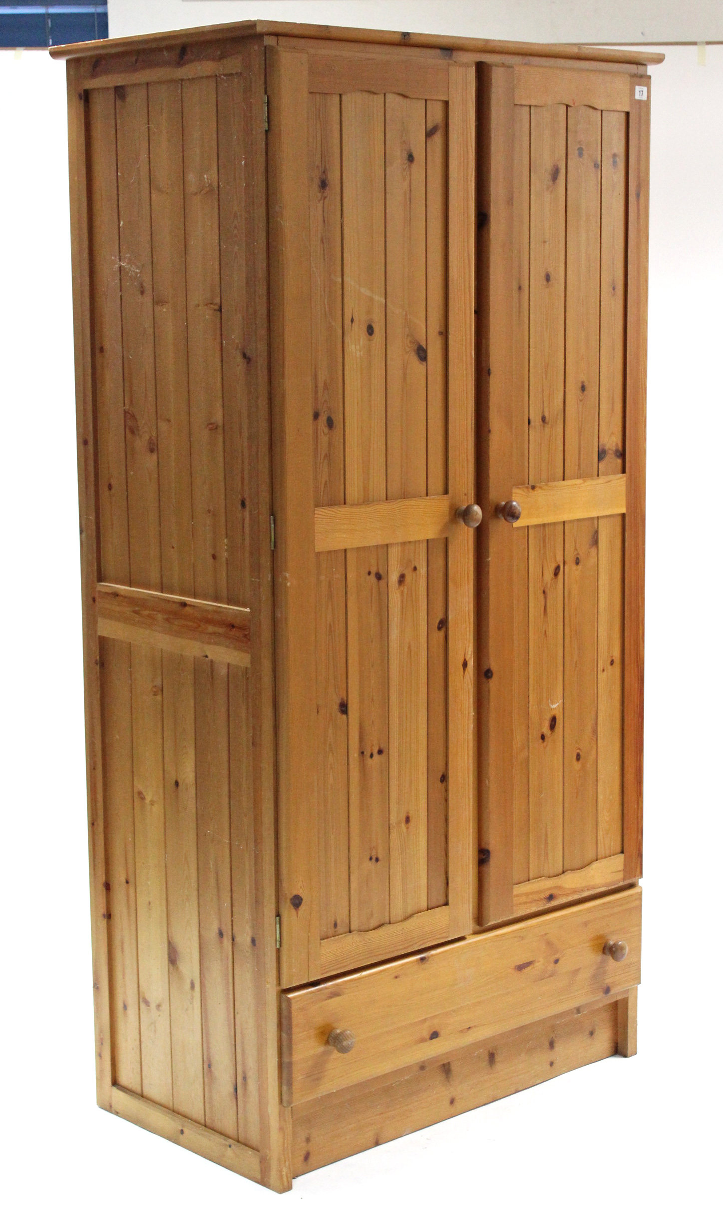 A pine wardrobe enclosed by pair of panel doors above a long drawer, 37” wide x 73” high.