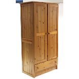 A pine wardrobe enclosed by pair of panel doors above a long drawer, 37” wide x 73” high.