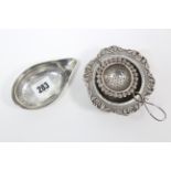 A George III silver pap boat, 4¼” wide, London 1803; & an Indian silver tea strainer & stand,