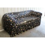 A Victorian chesterfield-style three seater settee upholstered floral material, & on turned feet