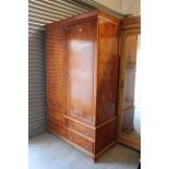 A yew wood finish wardrobe, enclosed by pair of panel doors above two ranks of two long drawers, &