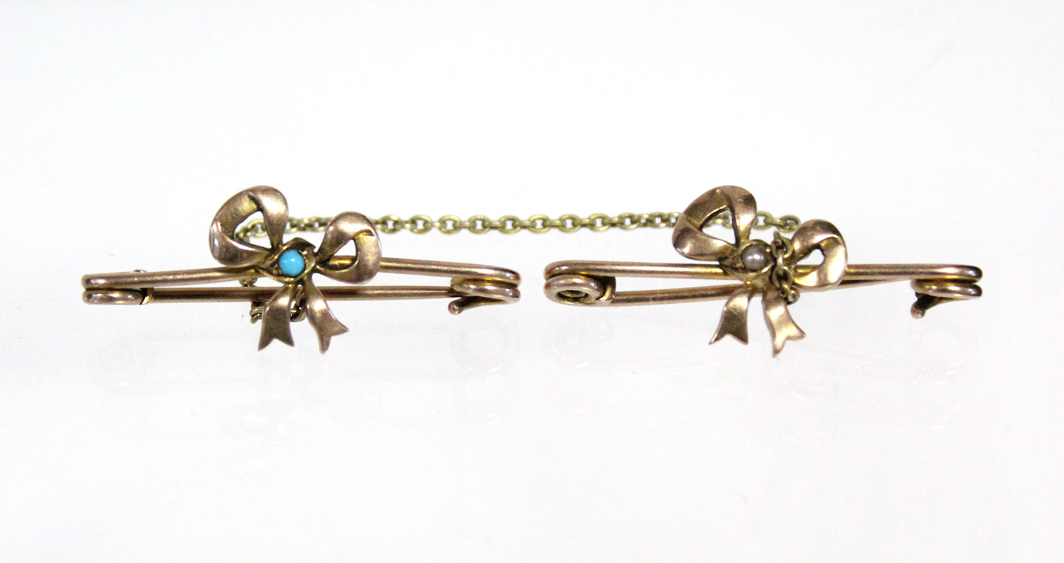 A pair of un-marked yellow metal ribbon-bow brooches connected by a 3½” length of fine-link chain;