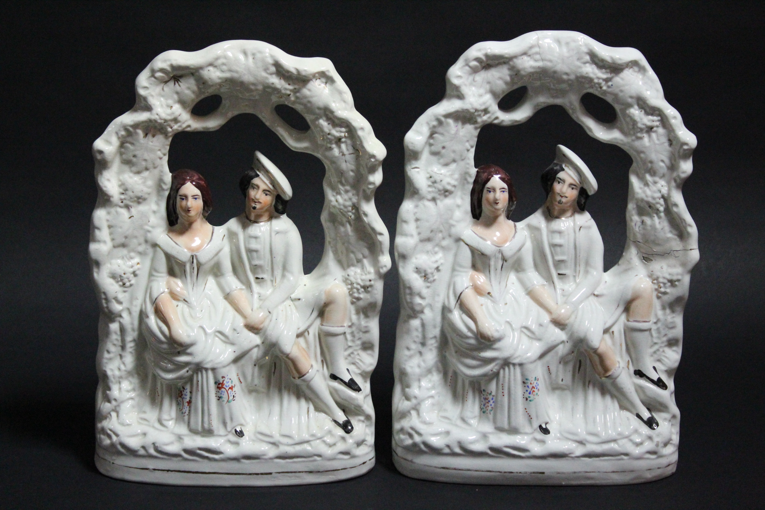 A pair of Staffordshire pottery flat-back models of male & female romantic figure groups; 14”