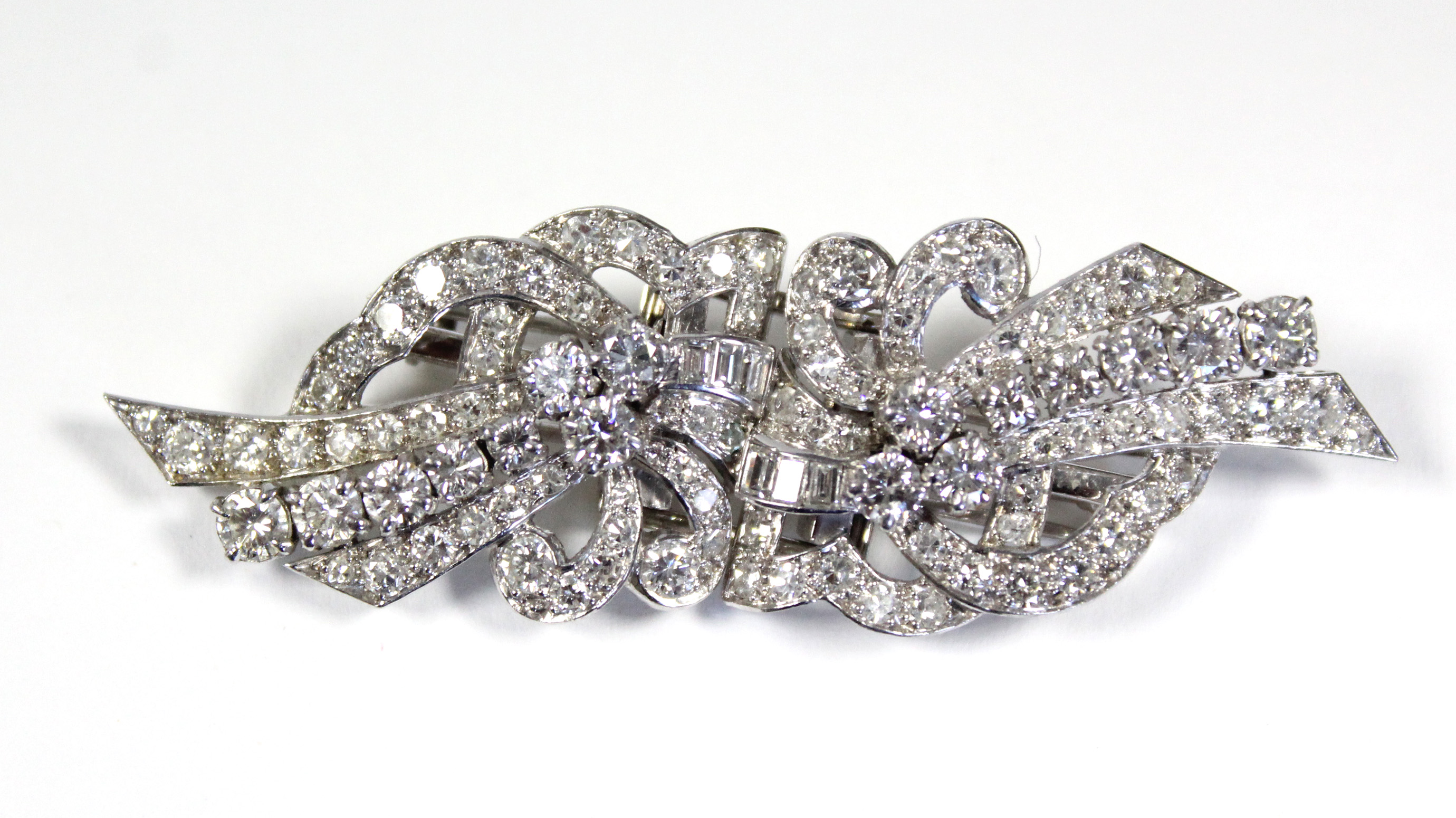 A PLATINUM & DIAMOND DOUBLE-CLIP BROOCH of scroll design, set approximately 102 round & baguette-cut