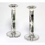 A pair of Edwardian silver-mounted candlesticks with embossed scroll decoration & green glass