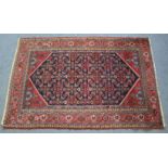 A Kirman rug of deep blue & crimson ground with central repeating geometric design surrounded by