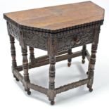 A 17th century-style carved oak credence table with fold-over top, shaped edge, fitted frieze