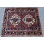 A Persian rug of dark blue & crimson ground, with two central ivory lozenges & all-over geometric