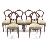 A set of six Victorian carved walnut dining chairs with open backs, padded seats, & on turned and