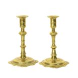 A pair of 18th century brass candlesticks, each with lobed drip-pan on slender baluster column &