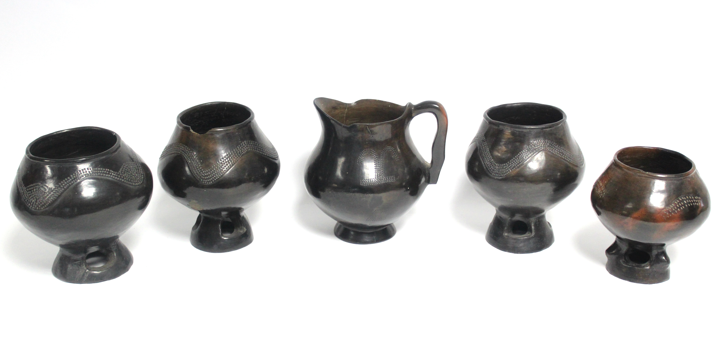 A group of four dark brown glazed earthenware vessels, each on pierced foot, 6” high; & a similar