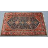 A Hamadan rug of dark blue & crimson ground, with central row of five medallions surrounded by guhls