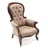 A mid-Victorian carved mahogany frame easy chair, the buttoned back, padded seat & arms